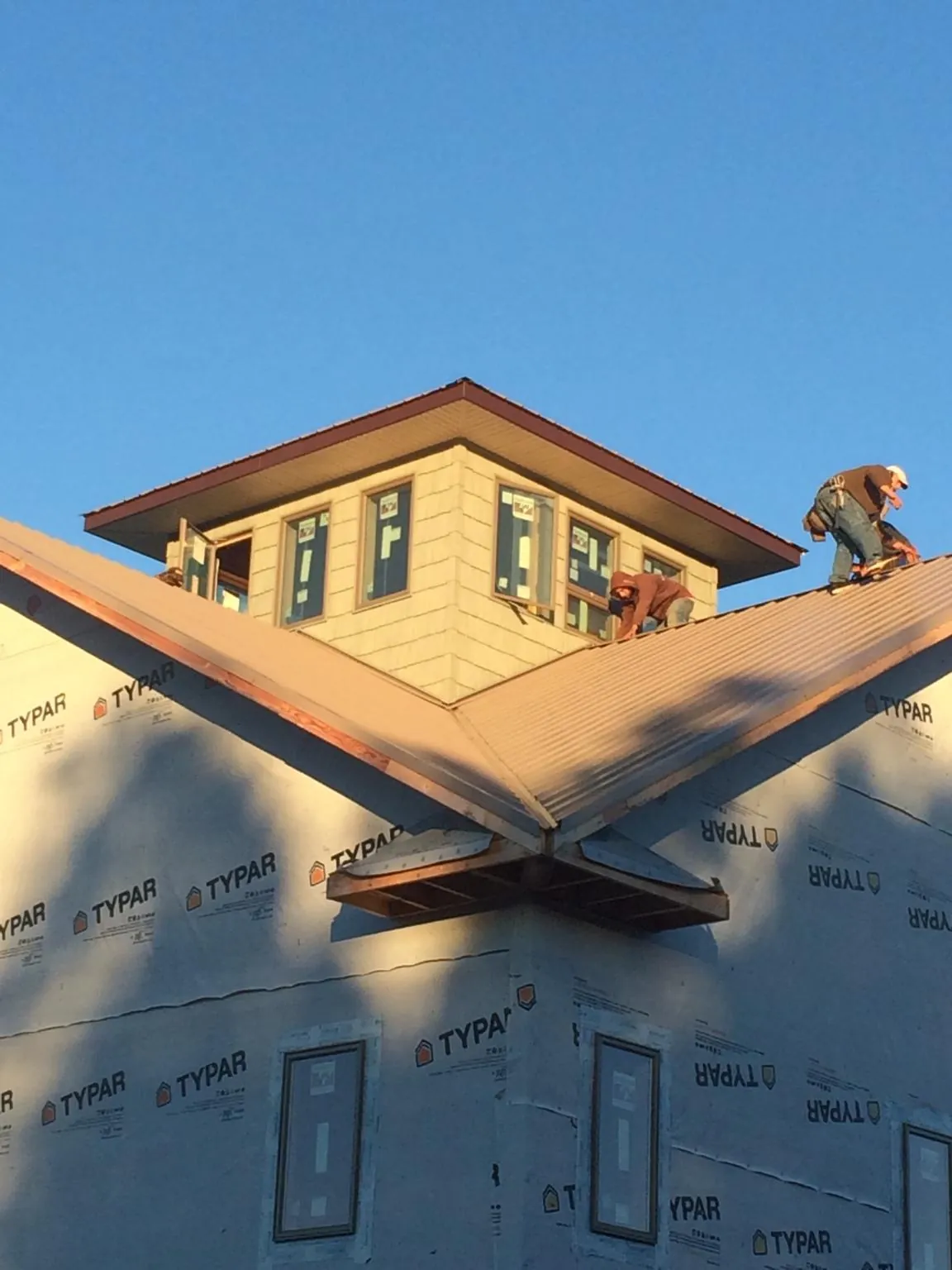 Roofers working around a rooftop cupola on a new metal roof at sunset — Roof Waterproofing in Delray Beach by Roofing Brothers